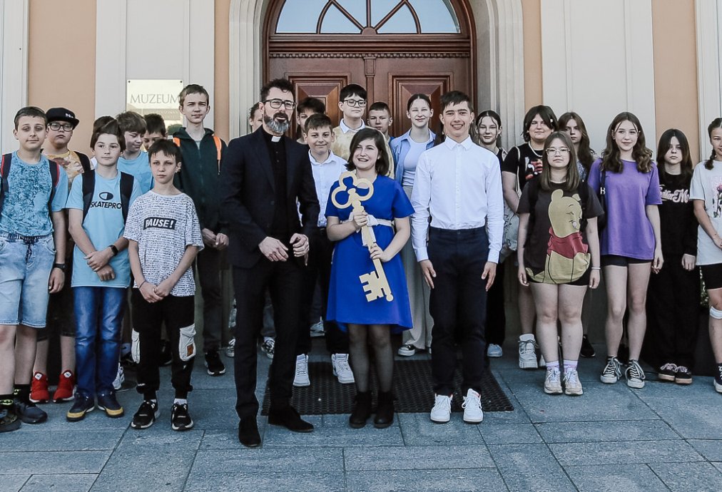 Grupa uczniów ze szkoły podstawowej nr 1 im. Jana Pawła II odbierająca klucze od dyrektora muzeum